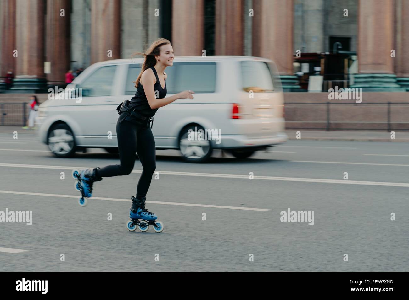 Happy smiling woman spends time in active way rides on skating rollers  demonstrated high speed during motion poses on roaad with transport in  Stock Photo - Alamy