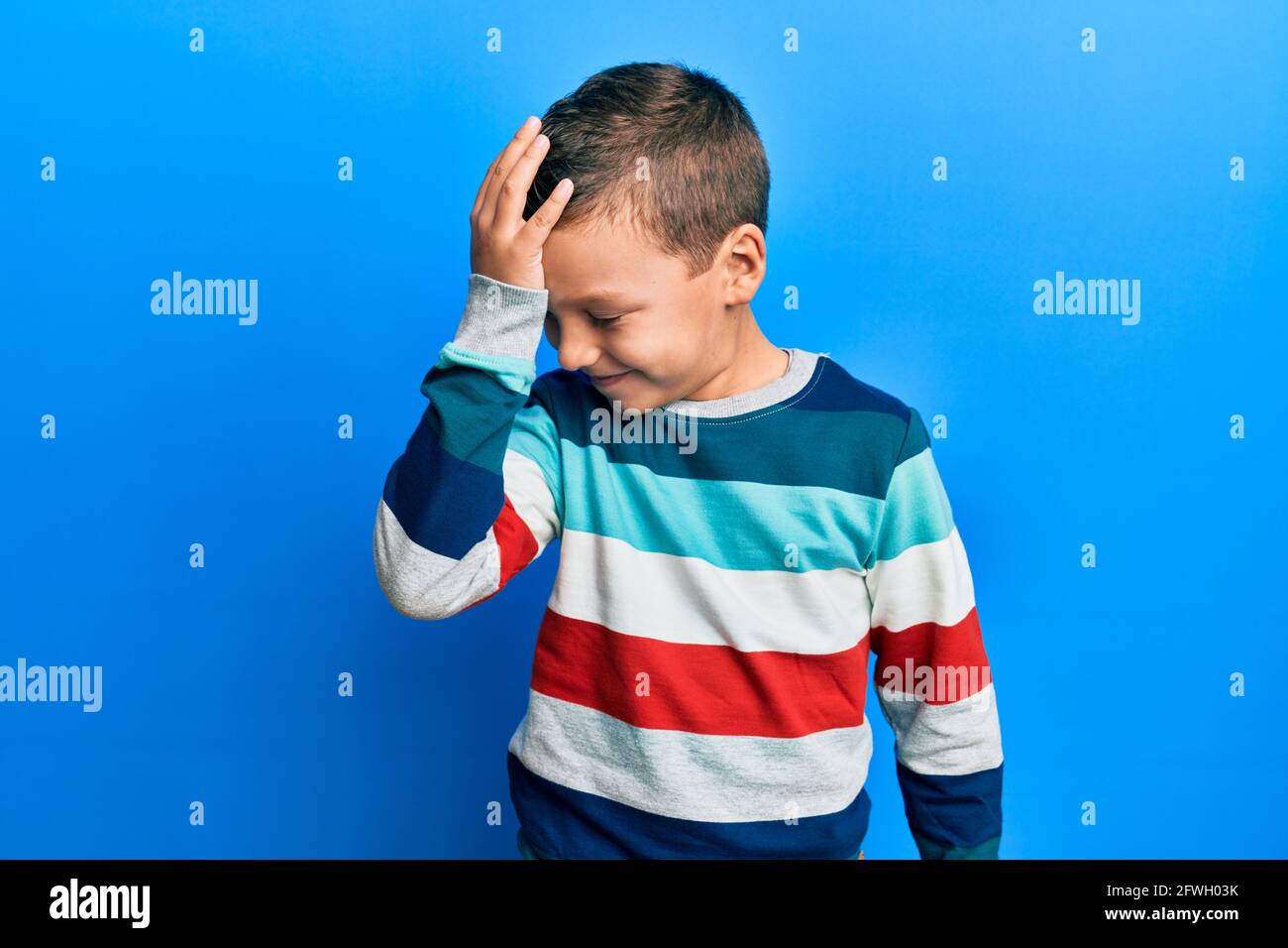 Little kid boy wearing striped sweater surprised with hand on head for ...