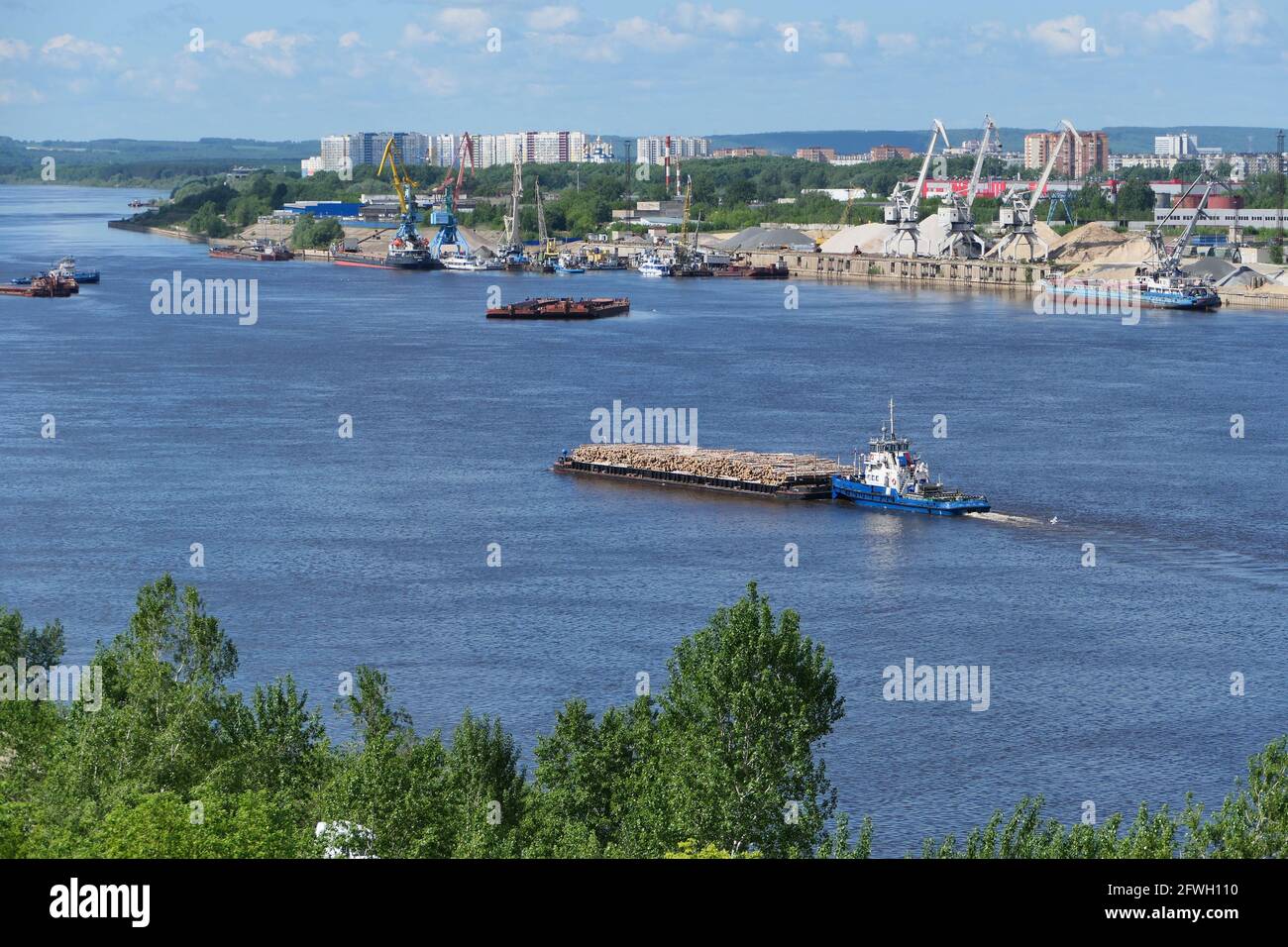 A barge carries cargo on the river. Transportation of wood by river transport. Stock Photo