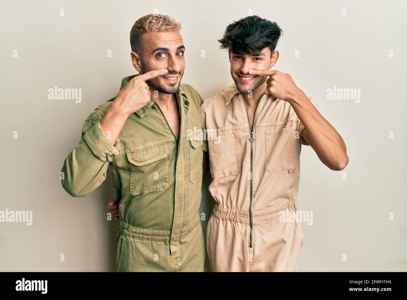 Homosexual gay couple standing together wearing casual jumpsuit pointing  with hand finger to face and nose, smiling cheerful. beauty concept Stock  Photo - Alamy