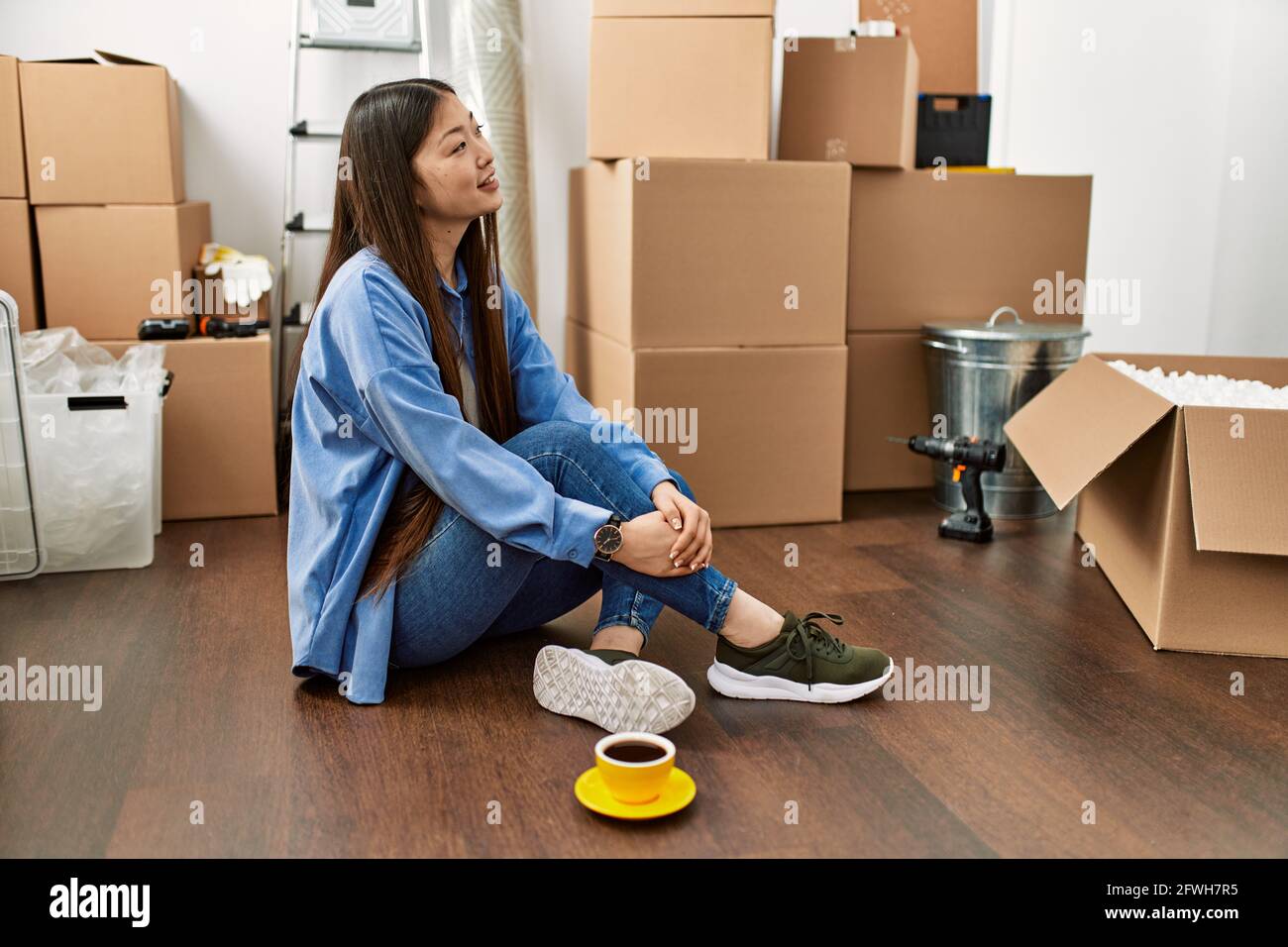 Young chinese girl smiling happy sitting on the floor at new home Stock ...