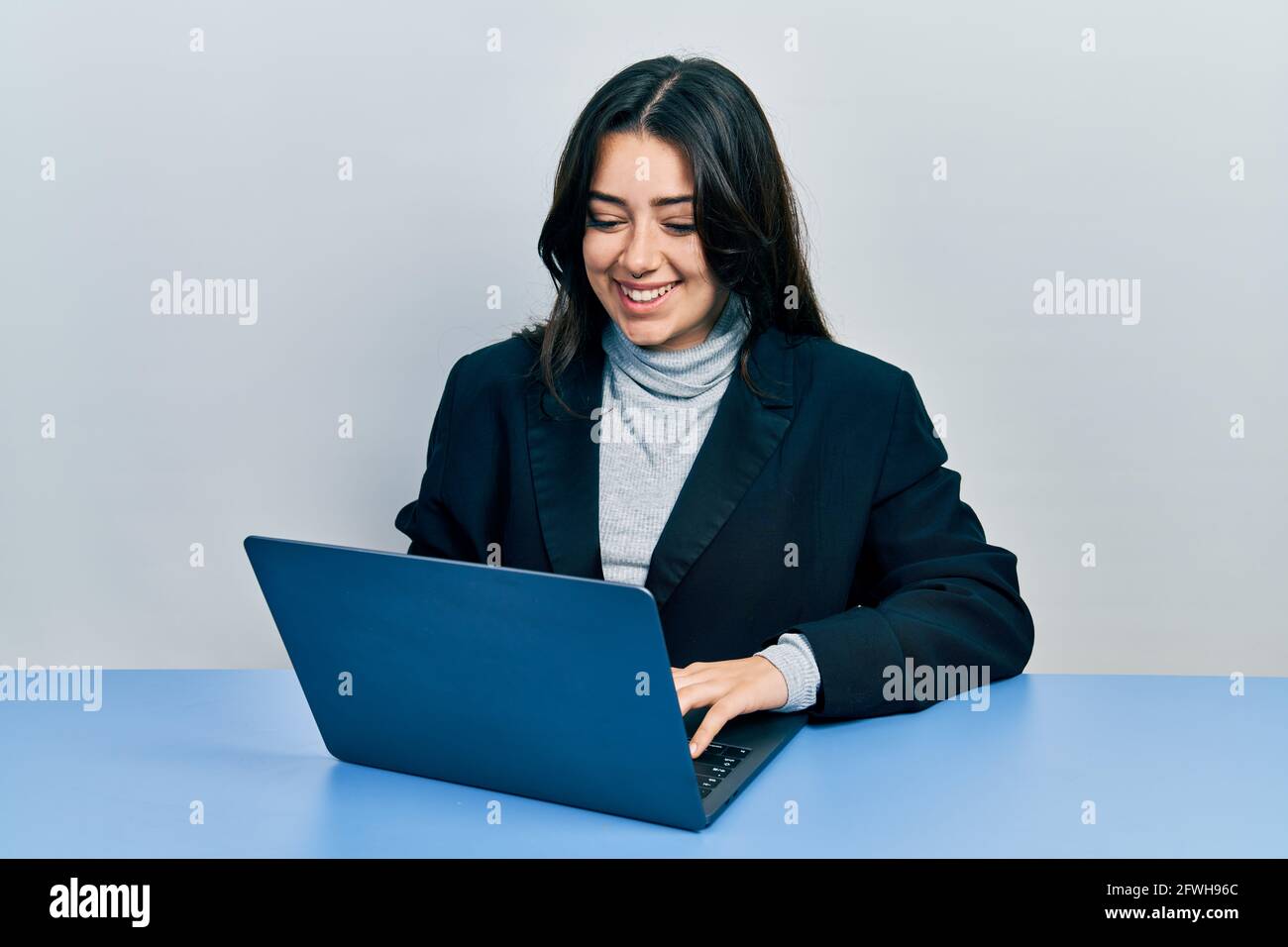 Beautiful hispanic woman working at the office with laptop smiling with ...