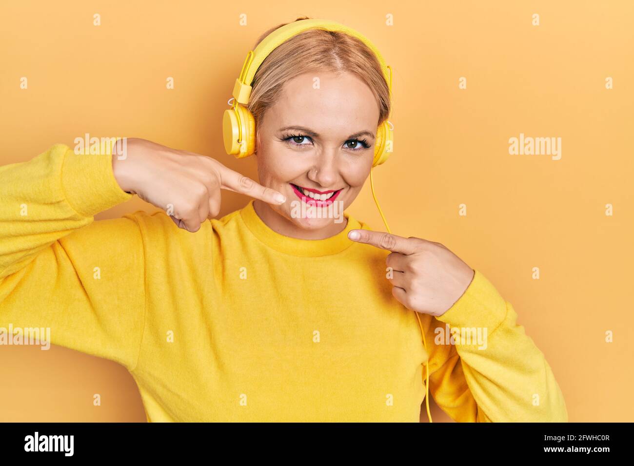 Young blonde woman listening to music using headphones smiling cheerful ...