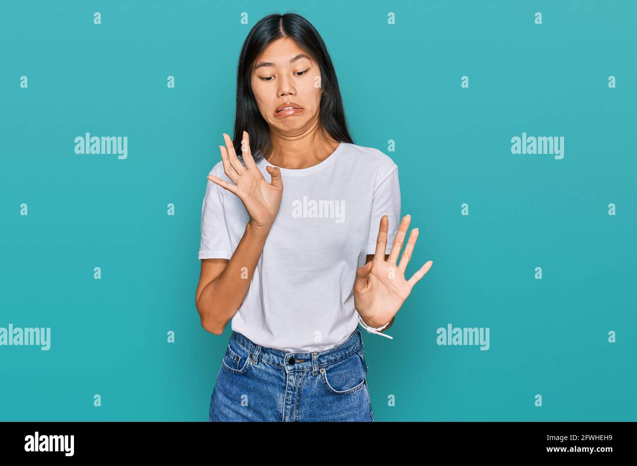 Beautiful young asian woman wearing casual white t shirt disgusted expression, displeased and fearful doing disgust face because aversion reaction. Stock Photo