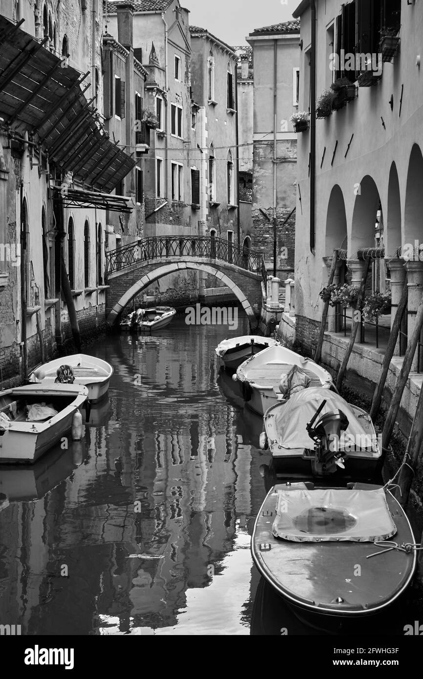 Canal in Venice with moored boats, Italy. Black and white photography, venetian view Stock Photo