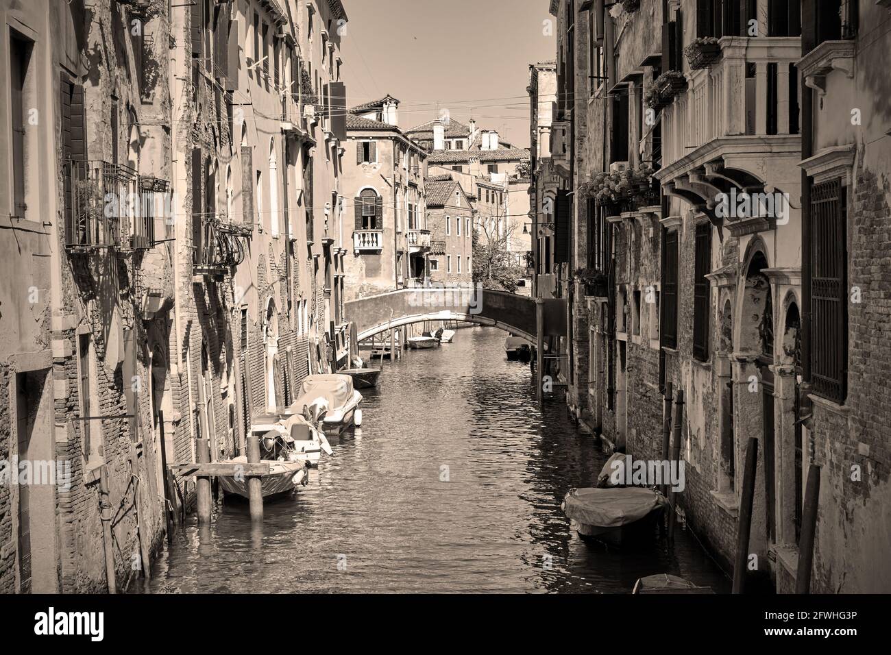 Canal in Venice with boats, Italy. Black and white sepia toned ...