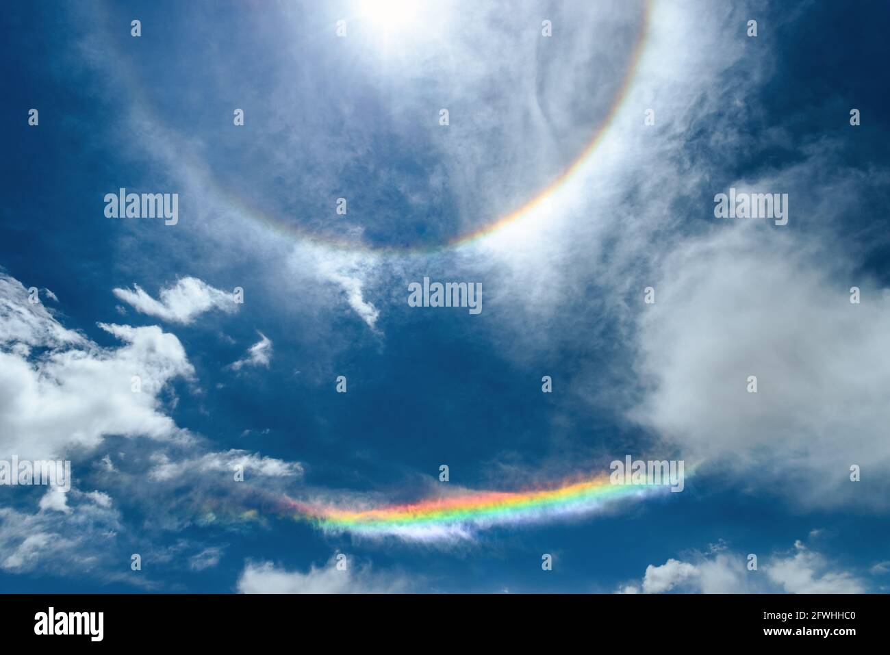 Solar halo phenomena and rainbow produced by light against the blue sky and clouds in Atacama desert, Chile Stock Photo