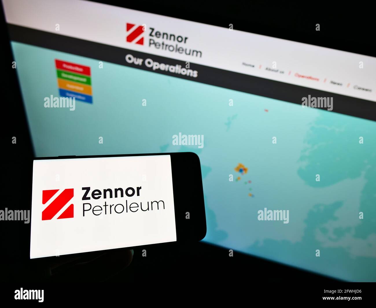 Person holding smartphone with logo of British oil and gas company Zennor Petroleum Ltd. on screen in front of website. Focus on phone display. Stock Photo