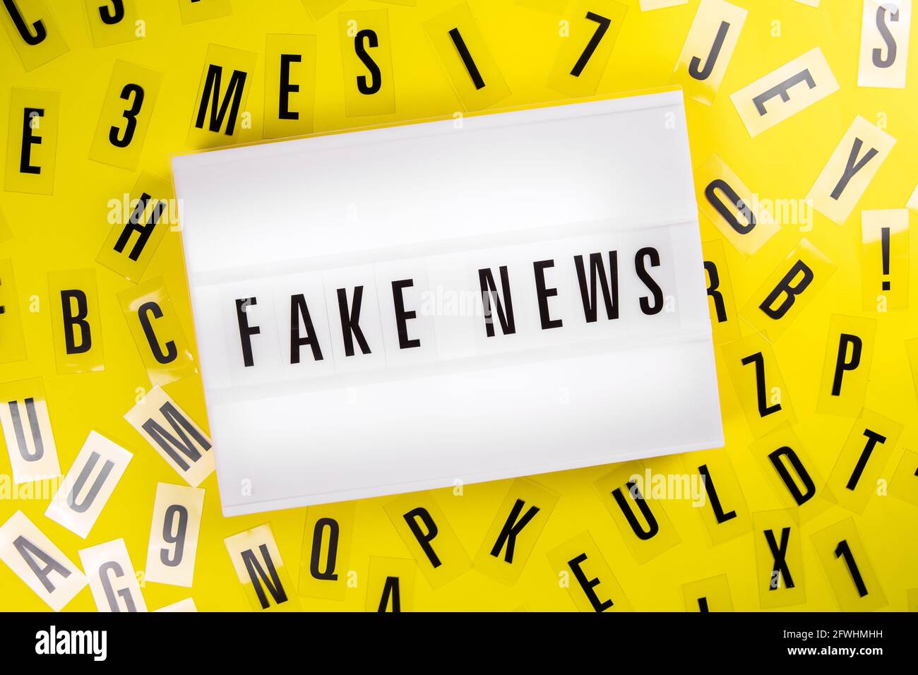 Lightbox with message FAKE NEWS on yellow background letters aroung, big lie Stock Photo