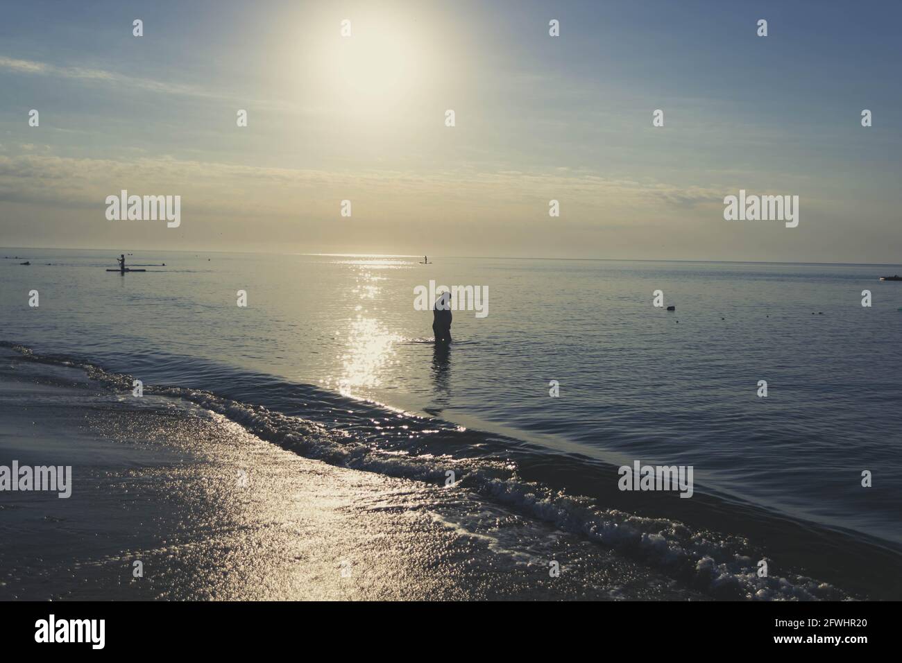 Silhouette of a fat man in the sea at sunset. Summer rest. Stock Photo