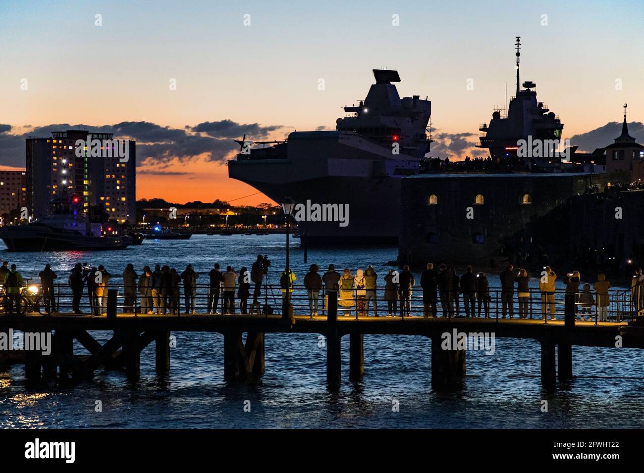 Dusk departure for HMS Queen Elizabeth from Portsmouth, UK on the 22nd May 2021 for the start of it's Carrier Strike Group Indo-Pacific deployment. F-35B Lightning II fighter aircraft are arranged on the flight deck of the ship. Stock Photo