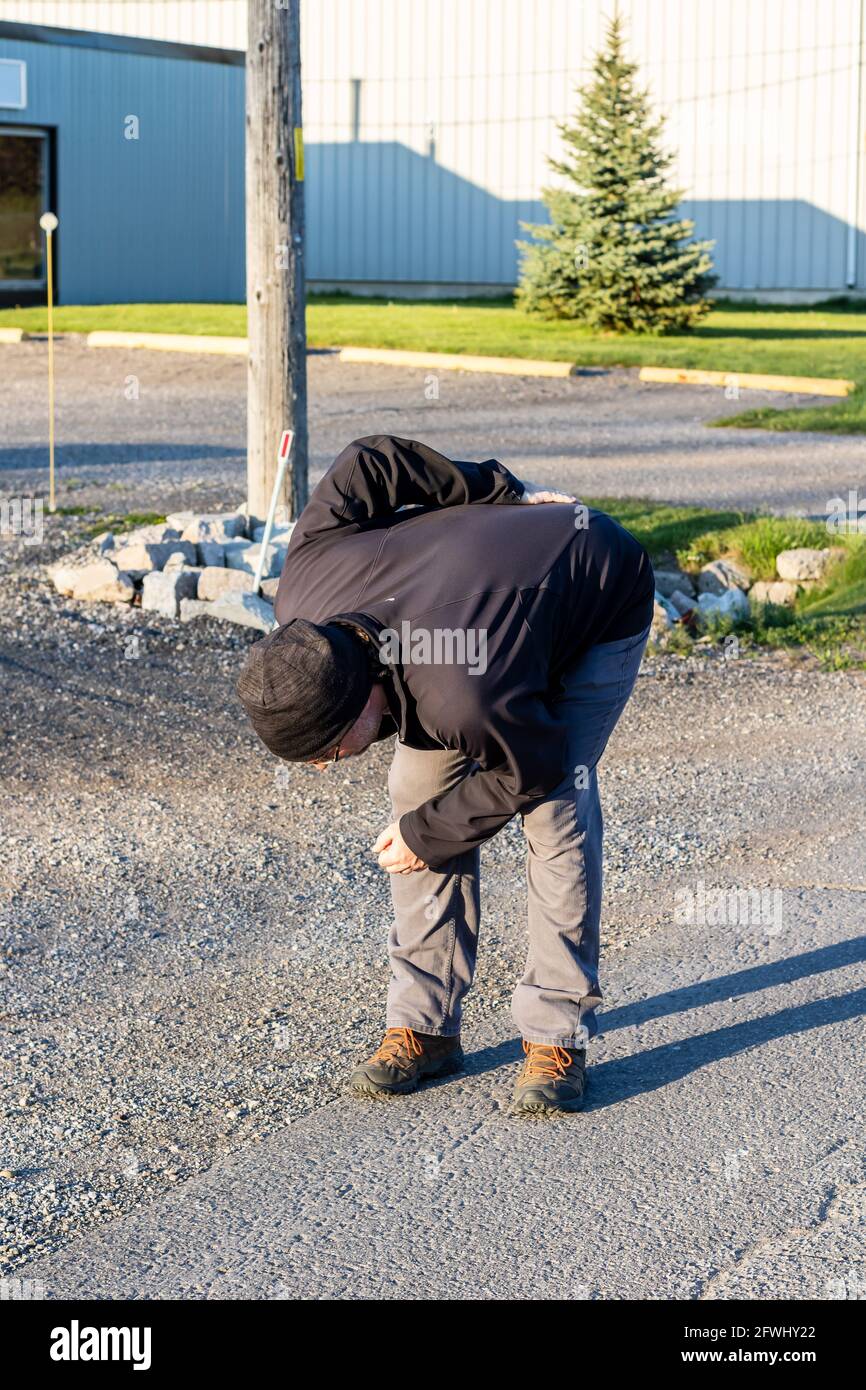 Middle aged Caucasian man in his 40s bending over and holding his back due to back pain Stock Photo