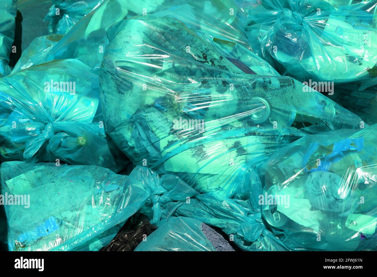 full frame background of turquoise green plastic trash bags with generic domestic waste Stock