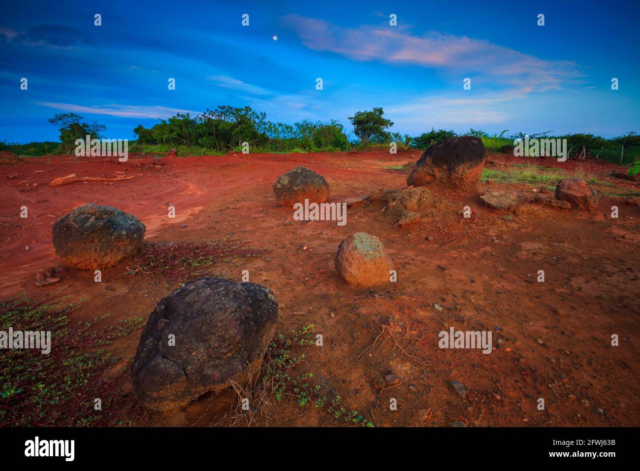 Panama landscape in evening light with moon, red desert soil, and large boulders in Sarigua national park, Herrera province, Republic of Panama. Stock Photo