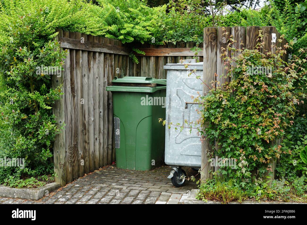 Metal container for house waste and plastic container for organic waste in a wooden niche. Stock Photo