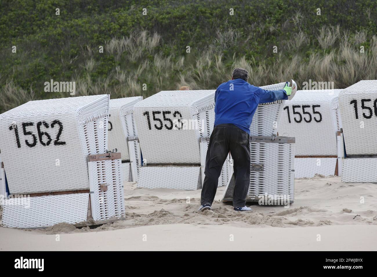 Westerland, Germany. 23rd May, 2021. An employee of the Sylt Tourism Service arranges rented beach chairs for a group. The tourist resorts in Schleswig-Holstein are well booked over the Whitsun weekend despite Corona-related restrictions and requirements. Credit: Bodo Marks/dpa/Alamy Live News Stock Photo