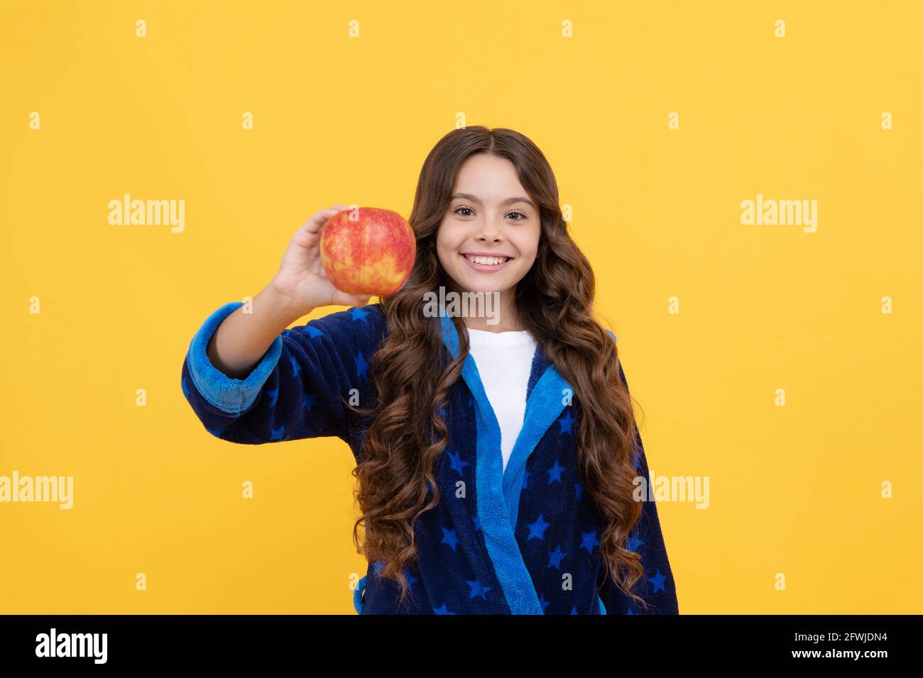 happy child girl enjoy morning breakfast of fresh apple in cozy bathrobe, organic food Stock Photo