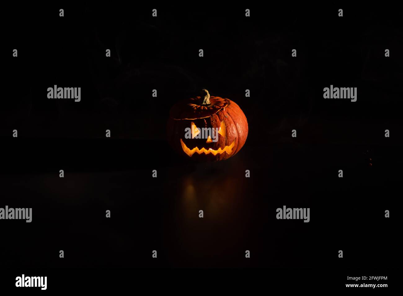 Halloween, orange pumpkin with a scary luminous face on a dark ...