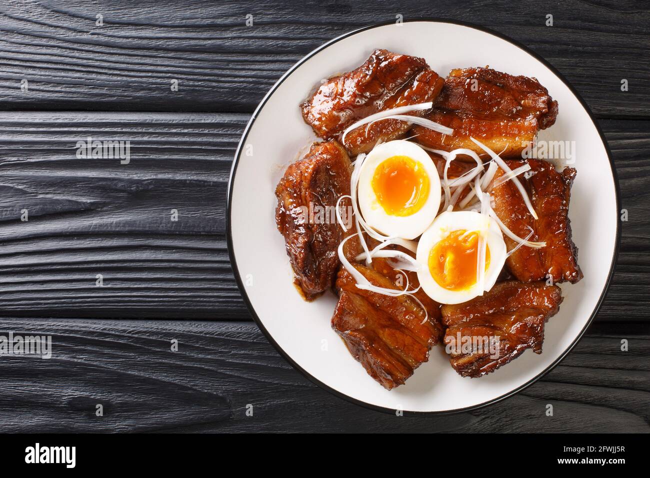 Japanese Braised Pork Belly with boiled eggs close up in the plate on the table. Horizontal top