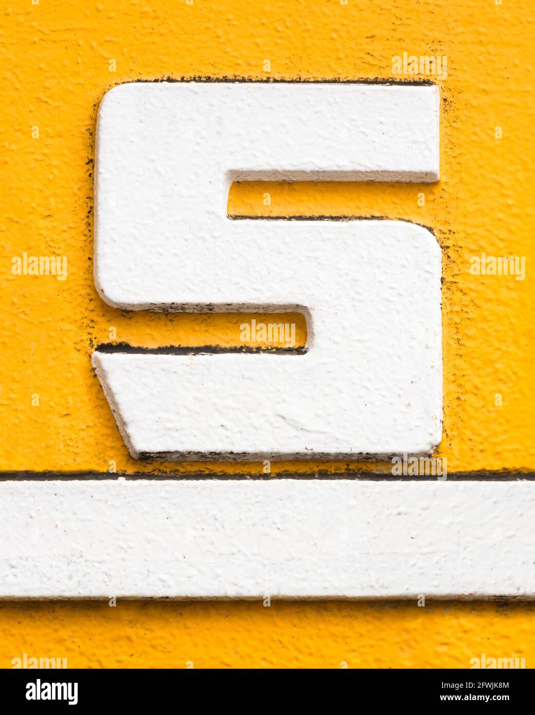 White metal letter S with white underline on yellow background Stock Photo