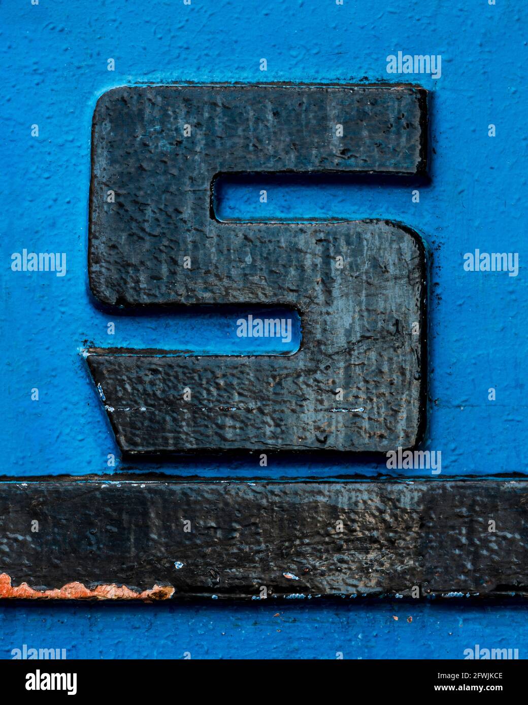 Black metal letter S with black underline on blue background Stock Photo
