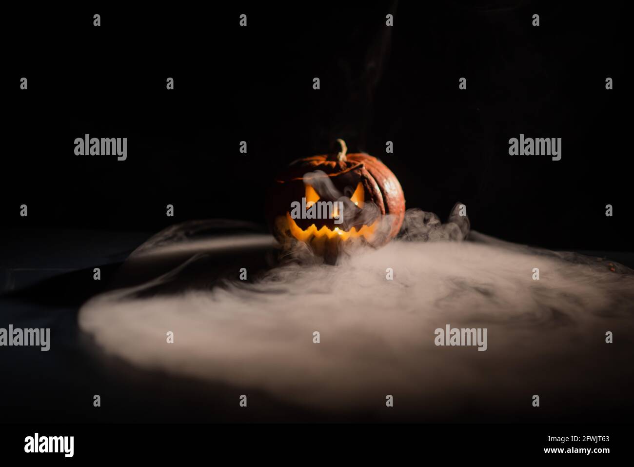 Halloween, orange pumpkin with a scary luminous face on a dark ...