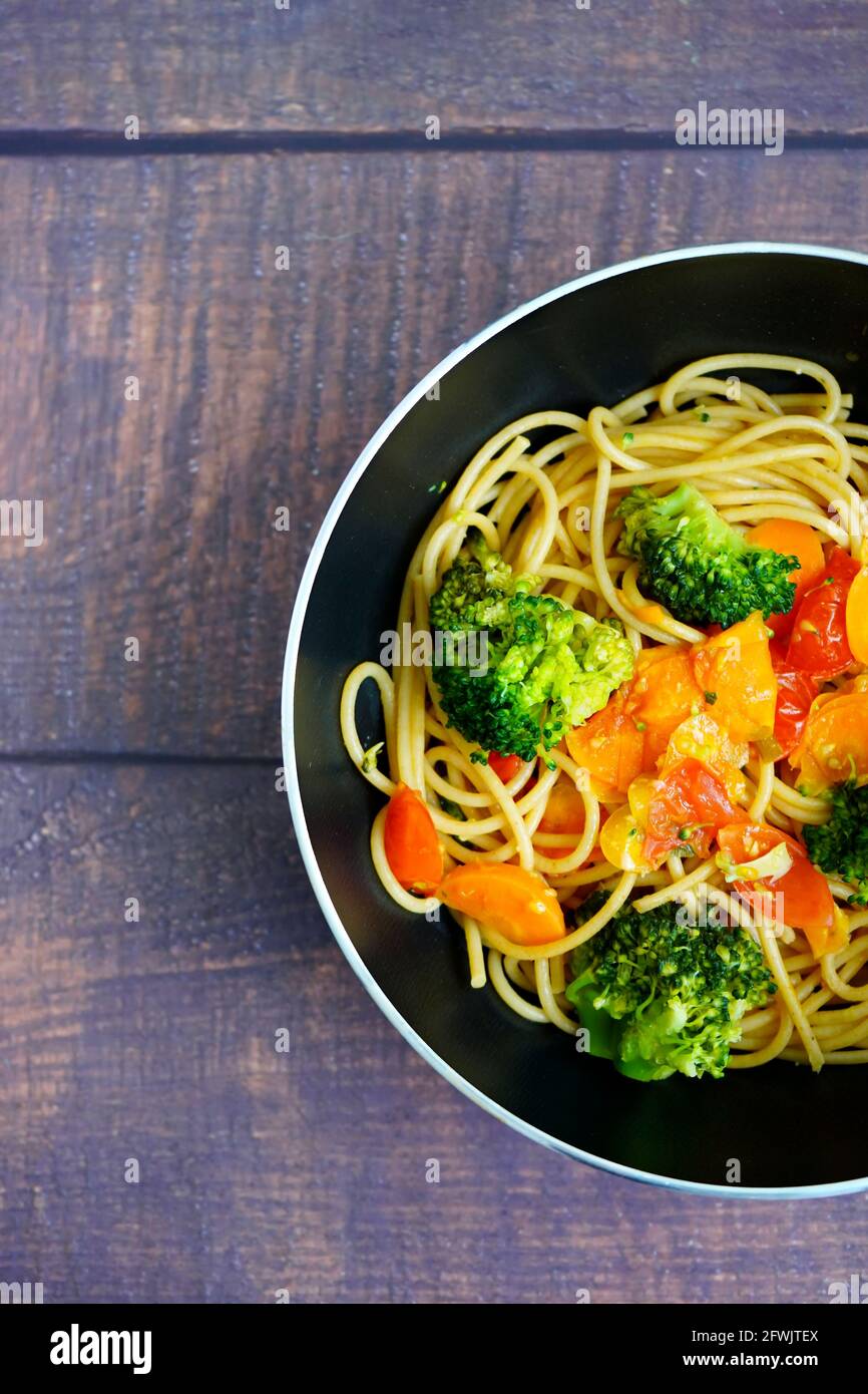 Healthy home cooking: Spagetthi with vegetables (brokkoli, tomatoes, carrots) in a frying pan. Stock Photo