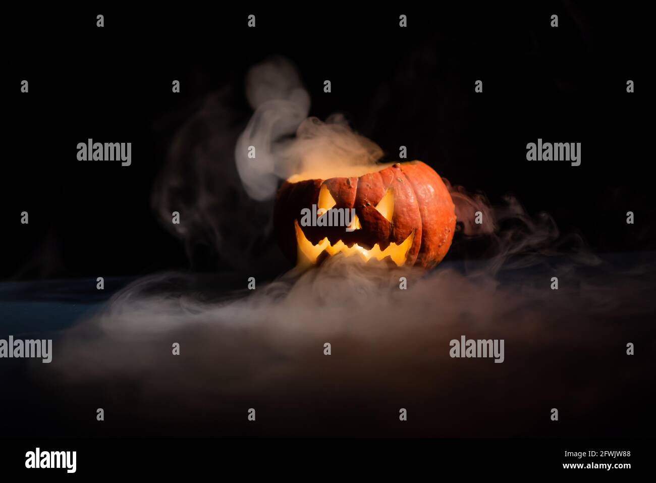 Halloween, orange pumpkin with a scary luminous face on a dark ...