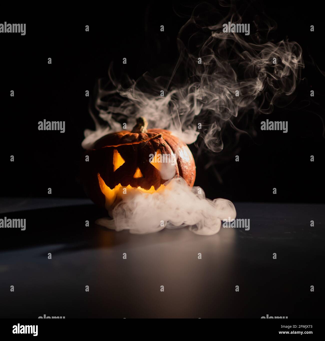 Halloween, orange pumpkin with a scary luminous face on a dark ...