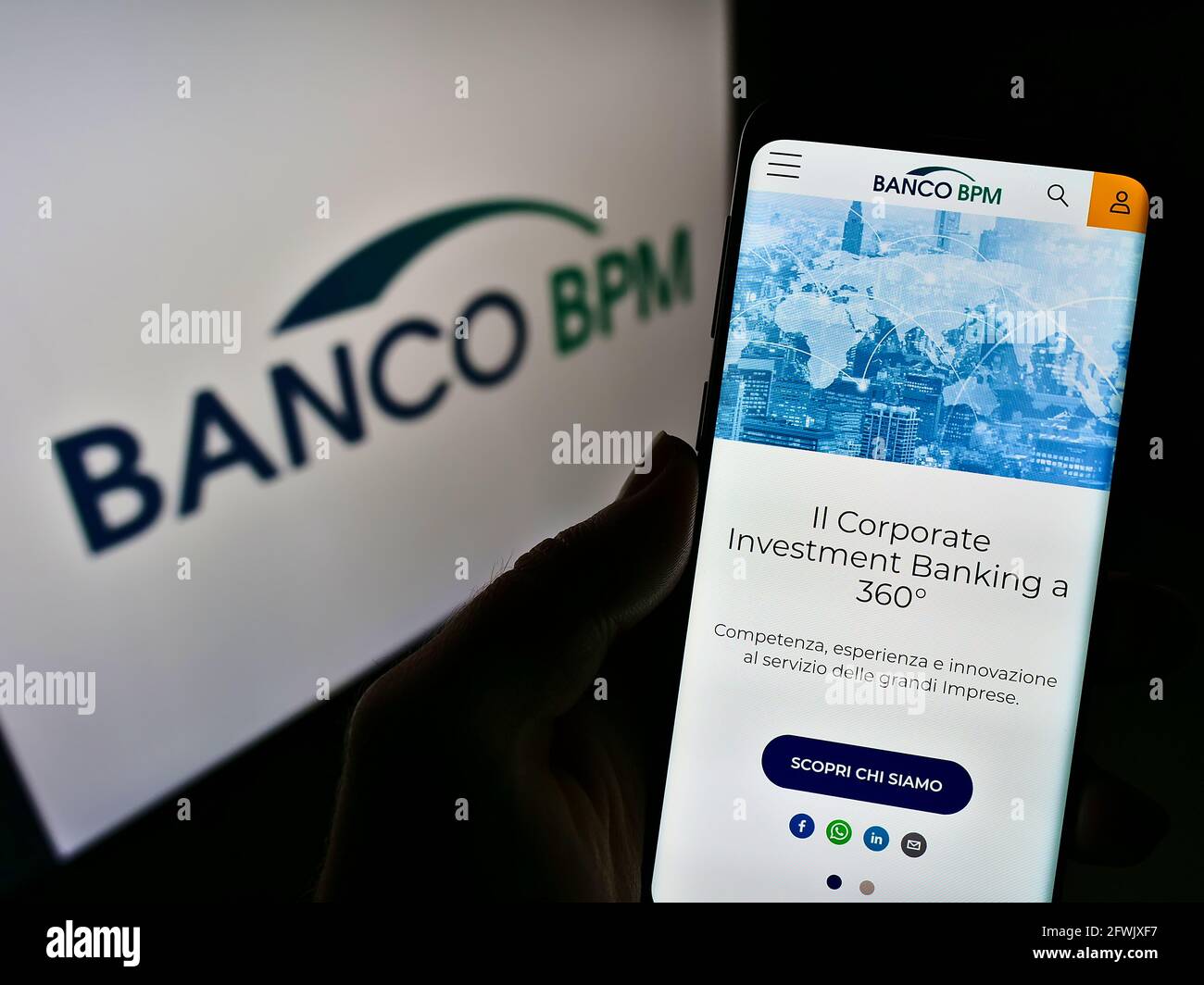 Person holding cellphone with website of Italian company Bank Banco BPM SpA on screen in front of business logo. Focus on center of phone display. Stock Photo