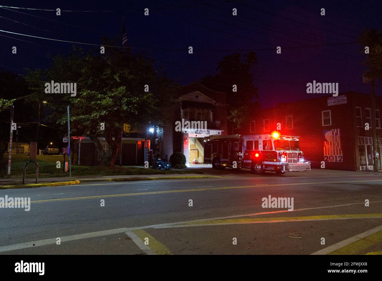 A fire truck leaving the station with its sirens and lights on at night