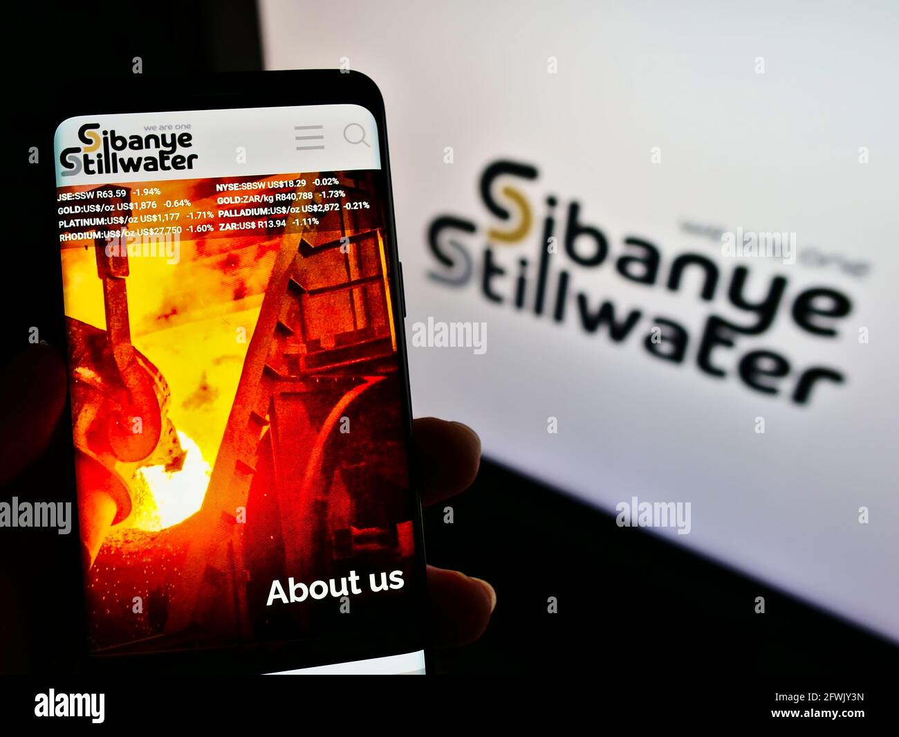 Person holding mobile phone with website of South African mining company Sibanye Stillwater on screen with logo. Focus on center of phone display. Stock Photo