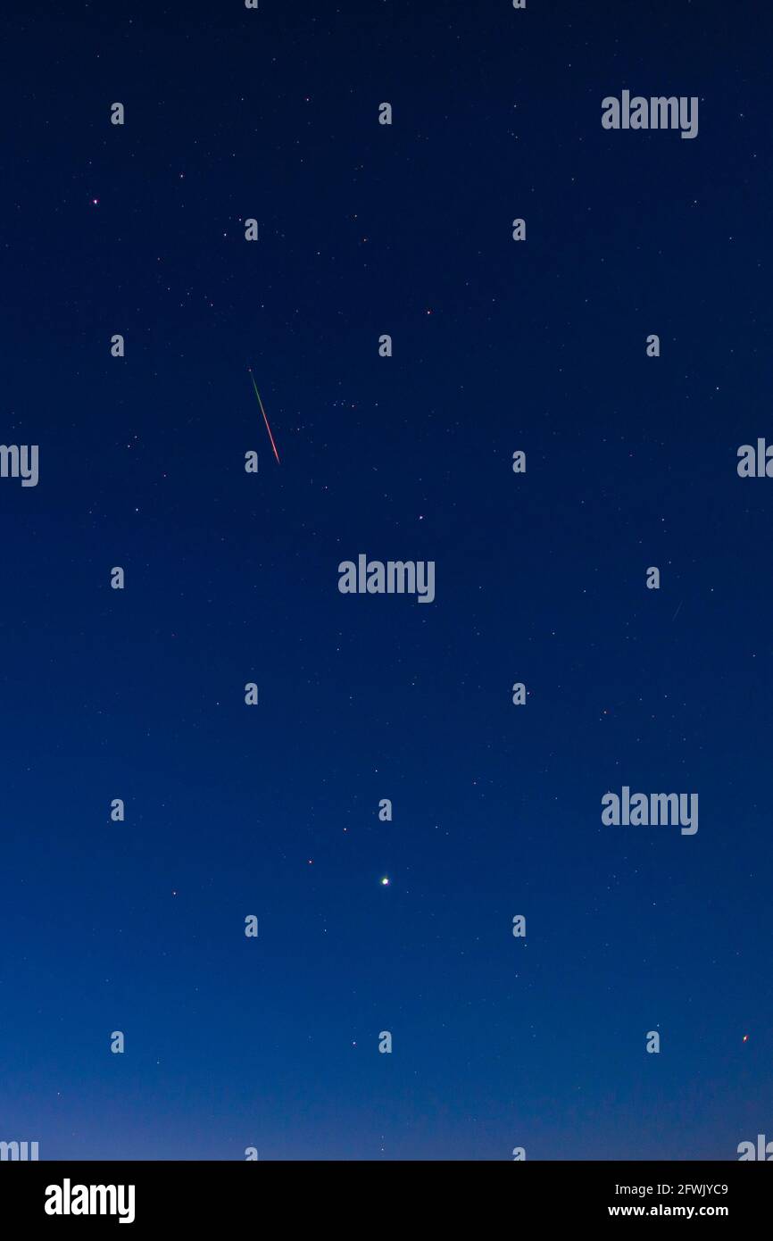 Bright red-green meteor of Perseid flow in the night sky Stock Photo