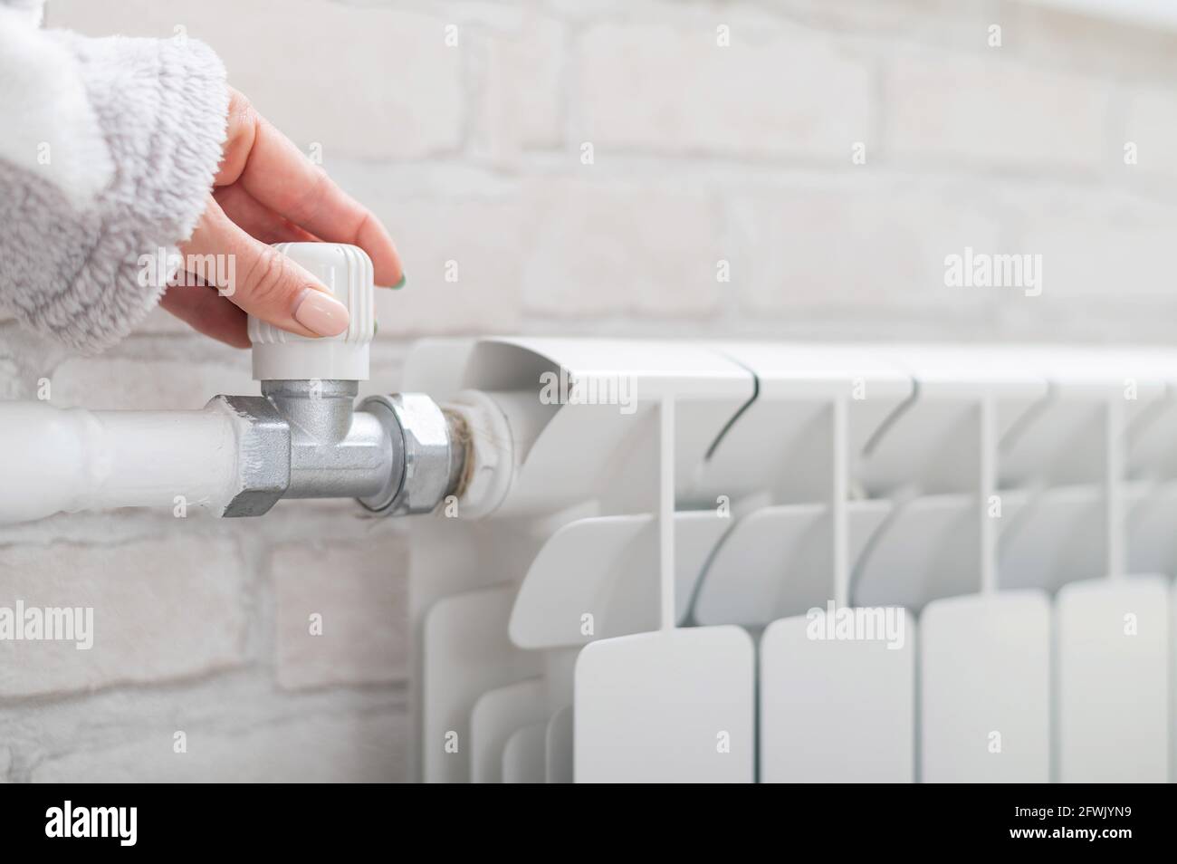 Close-up of a female hand regulating the temperature of a heating ...