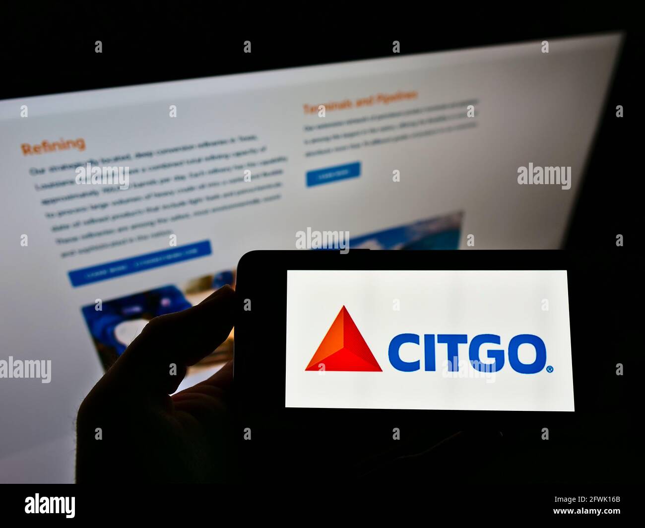 Person holding mobile phone with logo of US refining company Citgo Petroleum Corporation on screen in front of website. Focus on cellphone display. Stock Photo