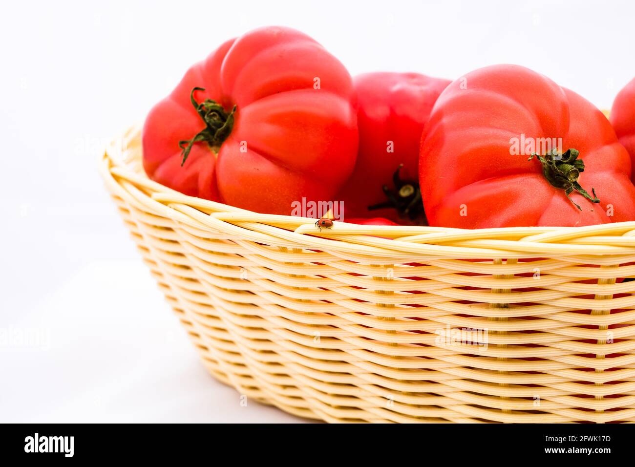 Fresh and tasty red tomatoes in wicker basket isolated Stock Photo - Alamy