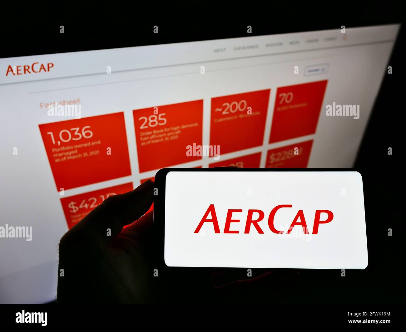 Person holding smartphone with logo of aircraft leasing company AerCap Holdings N.V. on screen in front of website. Focus on phone display. Stock Photo
