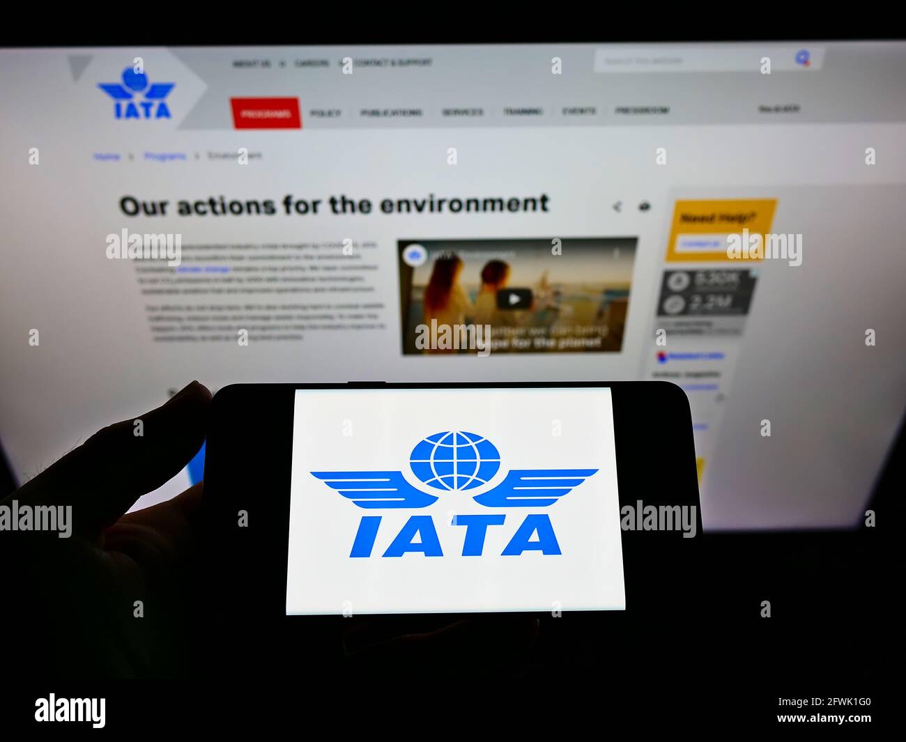 Person holding cellphone with logo of International Air Transport Association (IATA) on screen in front of web page. Focus on phone display. Stock Photo