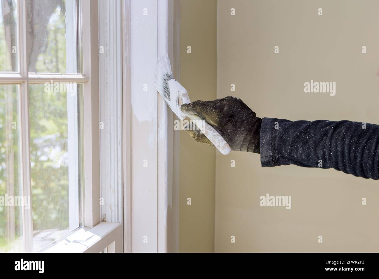 Home renovation in the handyman paints with a paint brush a window