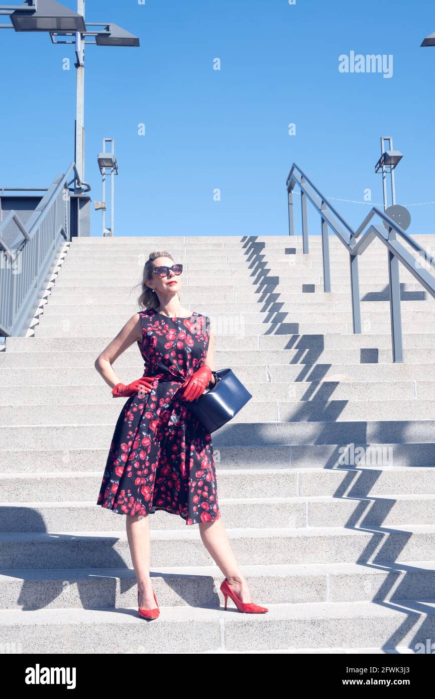 blonde woman in red dress and gloves holding purse and standing on stair  steps Stock Photo - Alamy