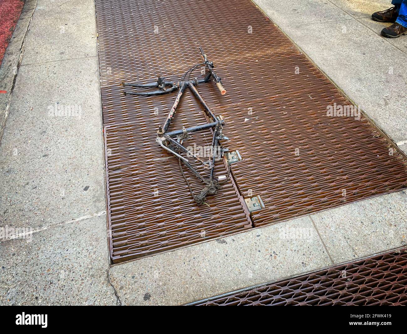 New York, NY, USA - May 23, 2021: The remnants of a trashed bicycle whose parts have all been removed lying on a subway grading Stock Photo