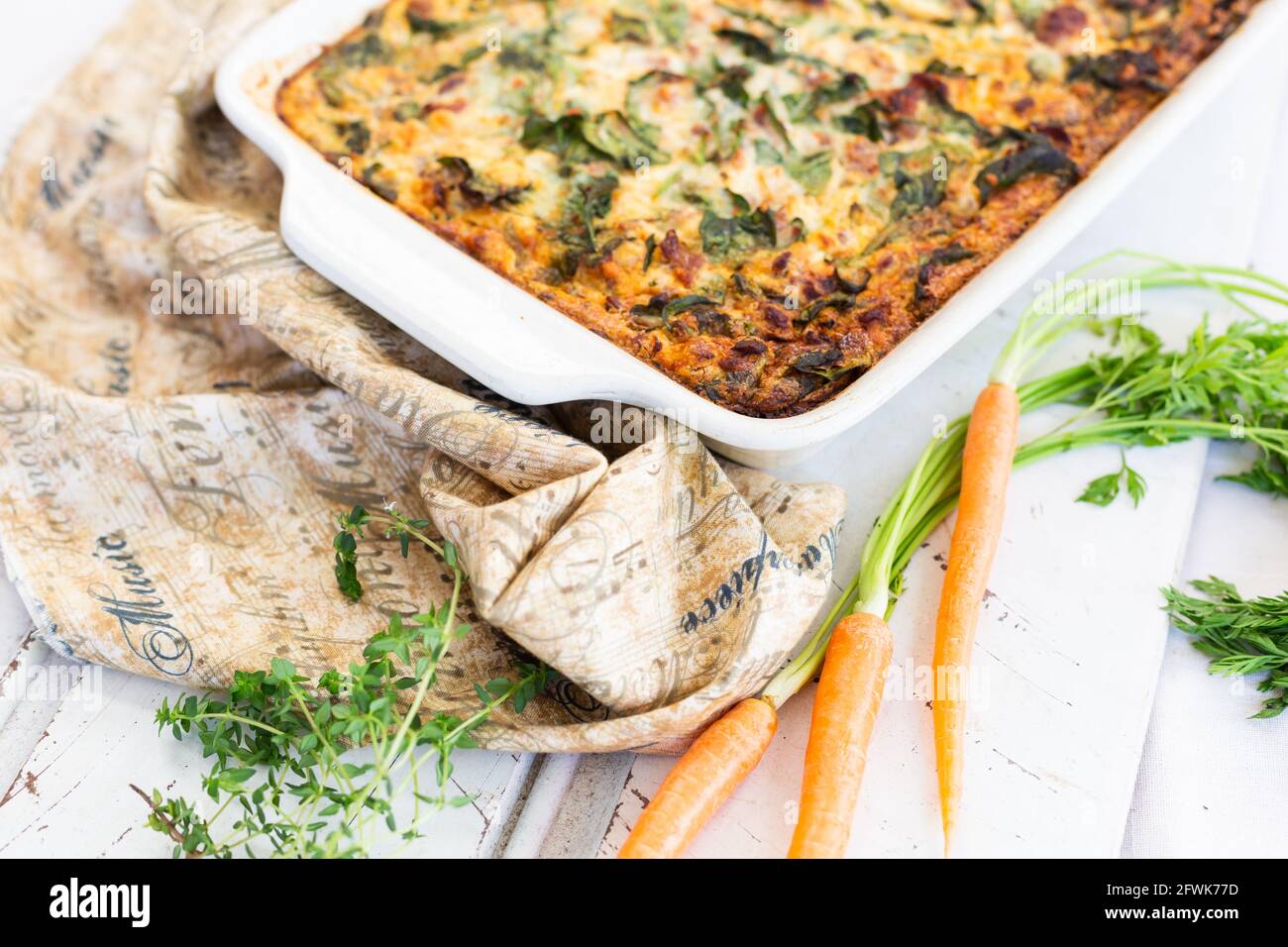 Frittata in pan with baby carrots and fresh thyme Stock Photo