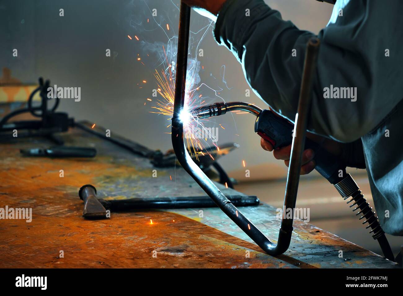 This is a welder working in a welding shop and sparks are flying. Close