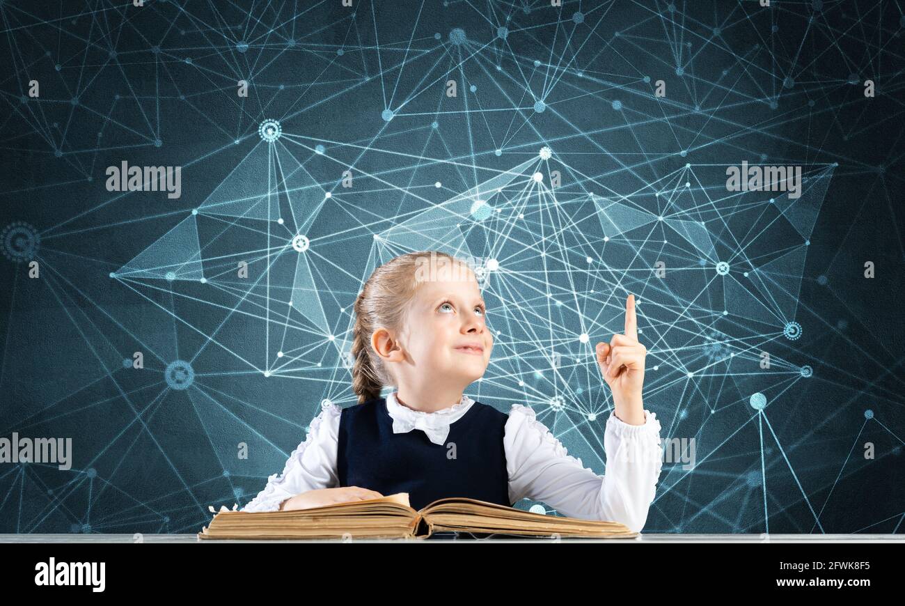 Smiling little girl sitting at desk with open book Stock Photo - Alamy