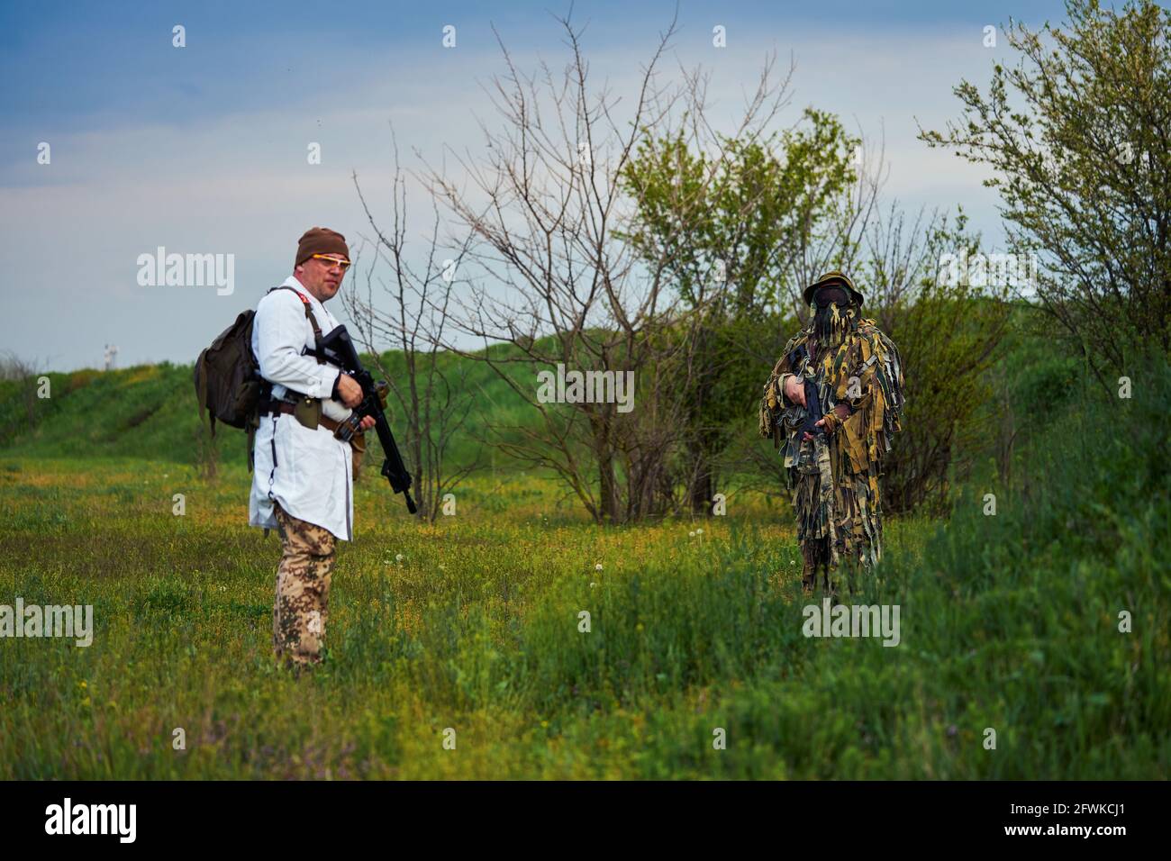 Airsoft players in the uniform of a medic and a sniper with weapons in their hands Stock Photo