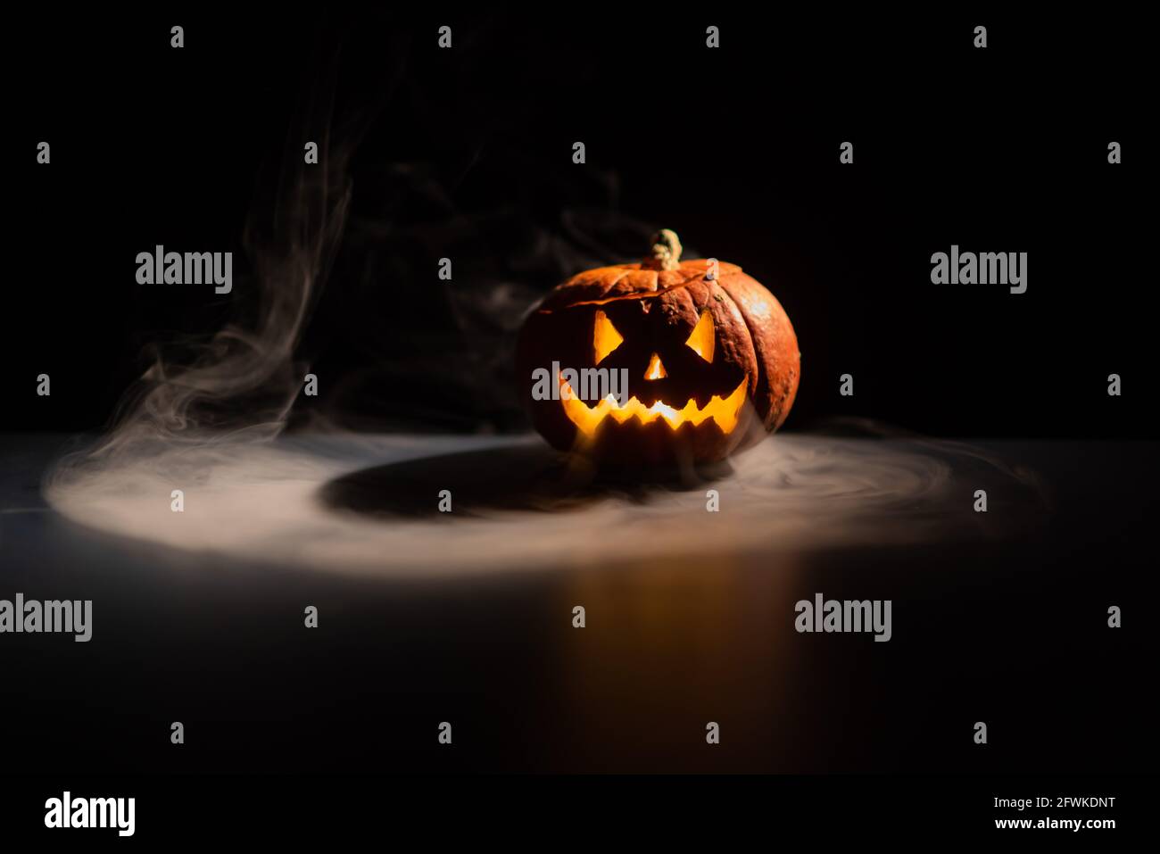 Halloween, orange pumpkin with a scary luminous face on a dark ...