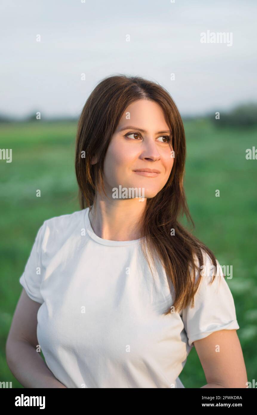 Beautiful young woman in a field at sunset. Woman smiling in nature Stock Photo