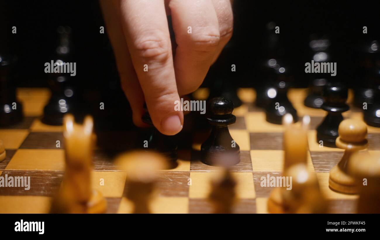 Person uses pawn on the board in chess game. Stock Photo