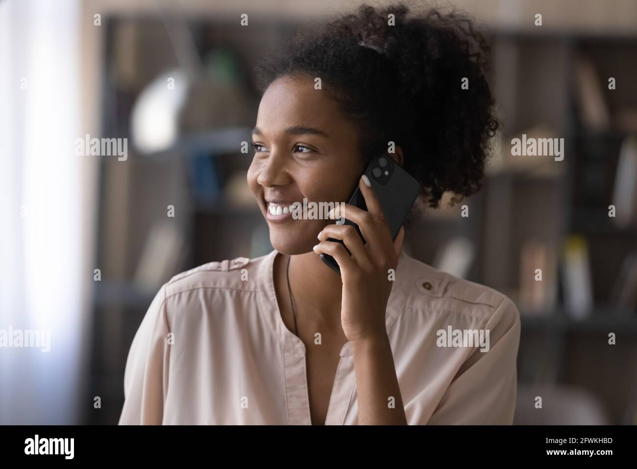 Smiling dreamy millennial african woman holding mobile phone call Stock ...