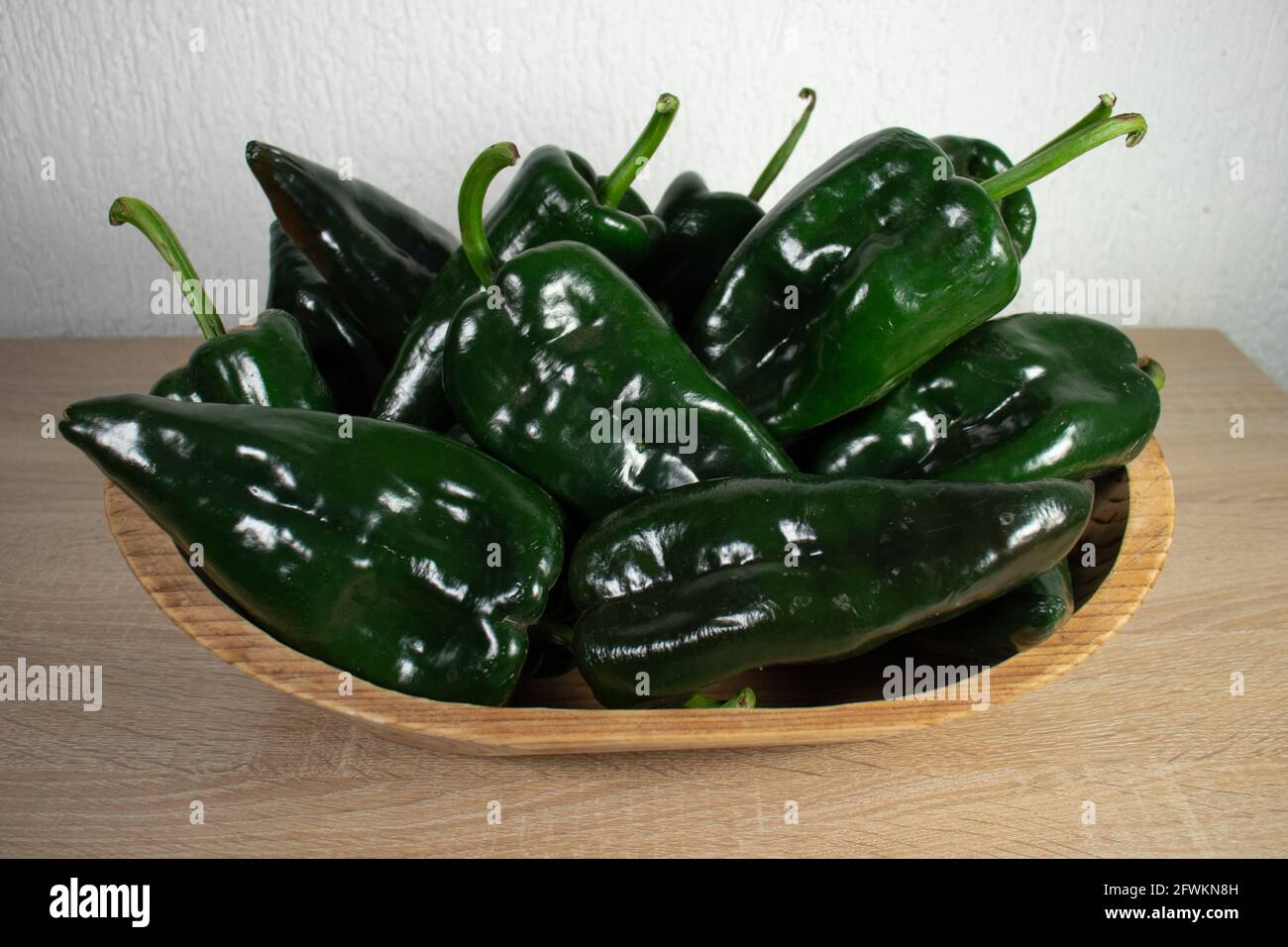Poblano Pepper's on a wooden basket. Wooden tray with poblano peppers. Chile Poblano. Stock Photo